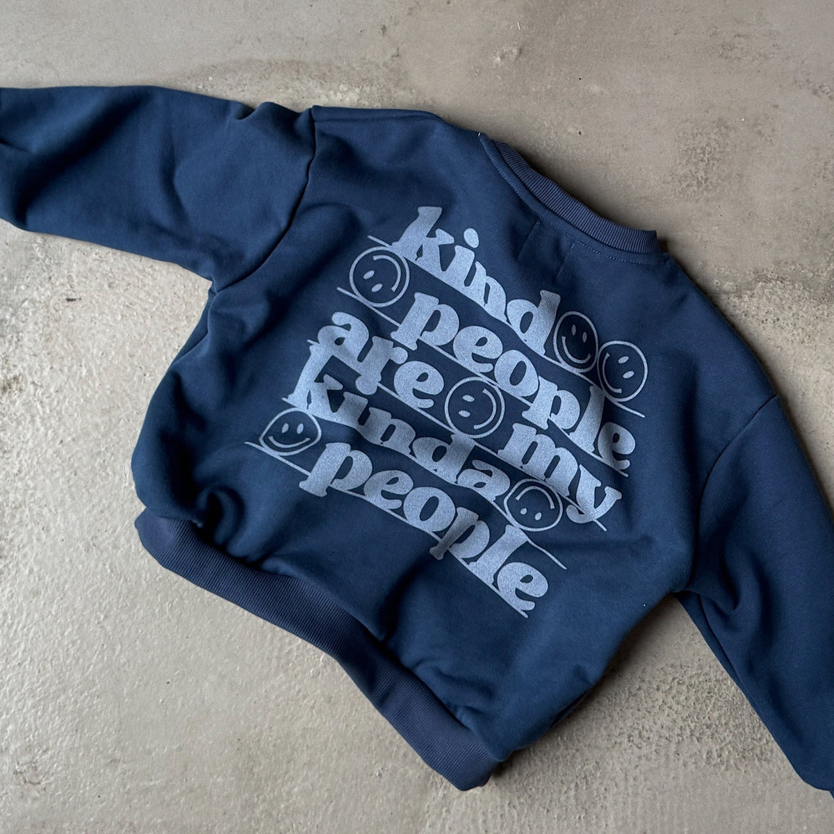 Blue hoodie with white text on a concrete surface